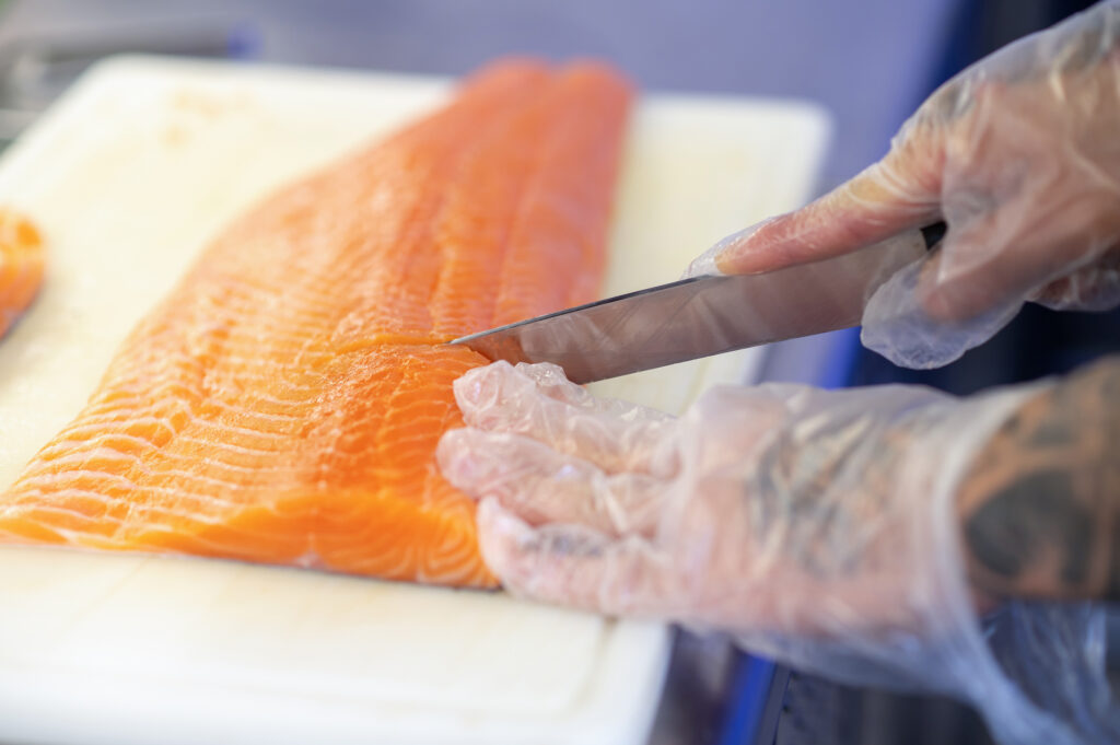 Close of mans hands cutting fish on a cutting board